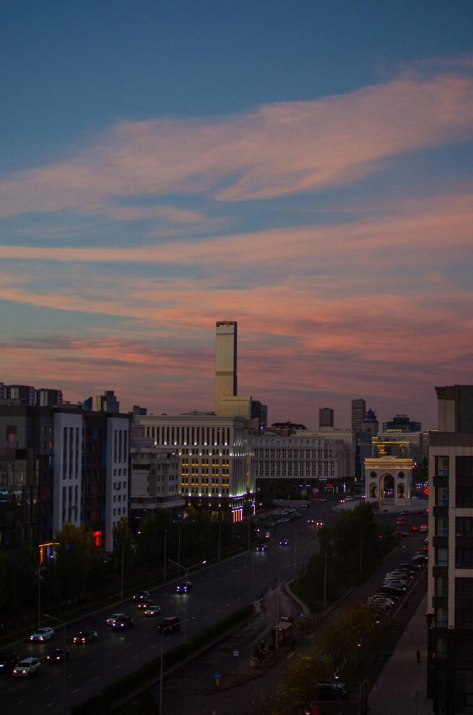 pexels-photo-19233202-19233202 Aerial view of Astana at dusk, showcasing modern architecture and vibrant city lights.