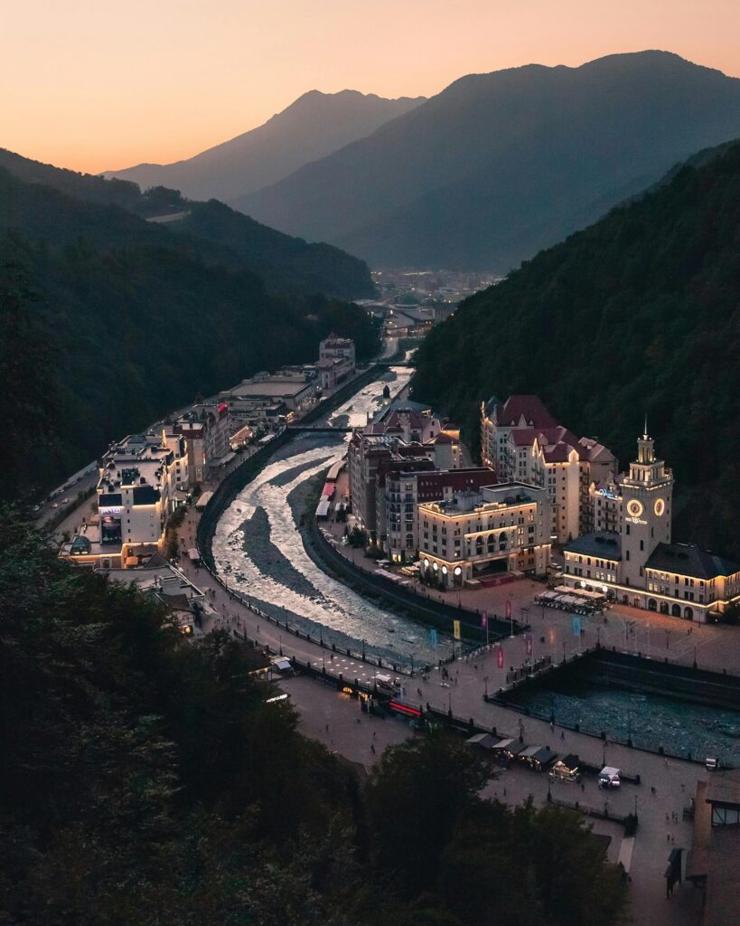pexels-photo-8443487-8443487 Aerial view of Rosa Khutor at twilight, nestled amidst mountains and river.